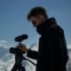 Cameraman at the top of a Mountain Prepping for an Interview in the Cold Snow in Italy