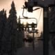 Promotional Photo of Skiers sat on chairlifts heading home for the day as the sun goes down with trees covered in snow either side